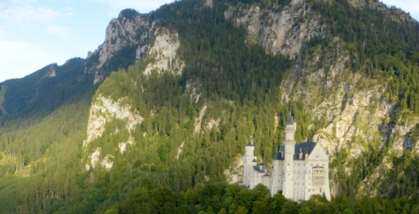 a woman walking towards an euro van by a cliff with many hot air balloons floating in the distance